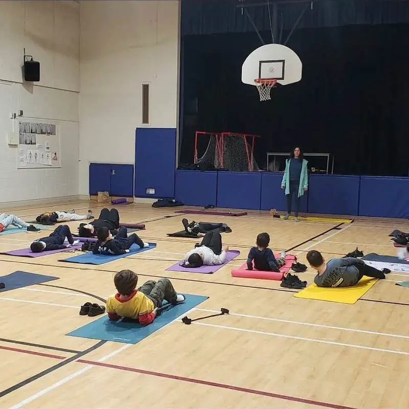 Students resting on mats in a school gym during a mindfulness session