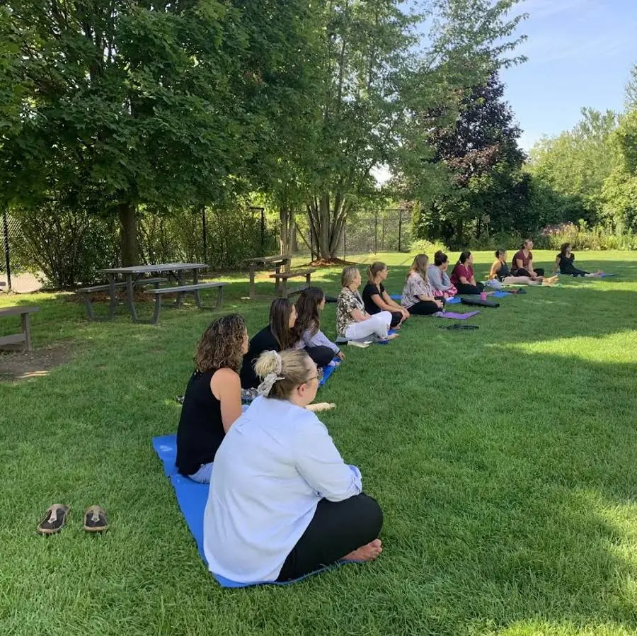 Adults practising seated meditation on mats in a park